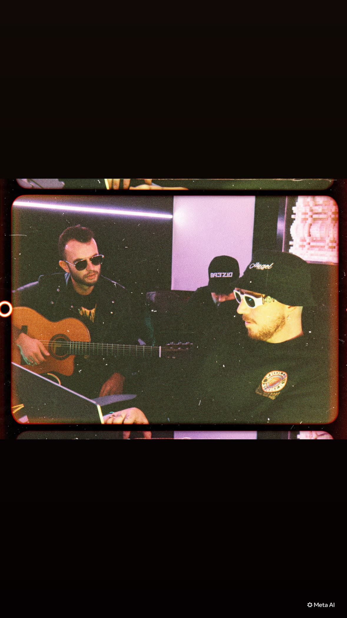 GRAUX playing acoustic guitar with collaborators in a studio